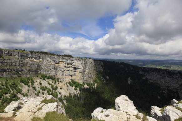 Dunkle Wolken hängen über dem Felsenkessel des Creux du Van oberhalb Noiraigue im Juragebirge.