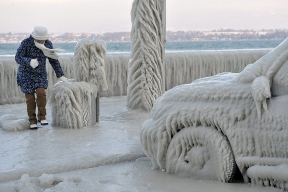 A woman walks along an ice covered car on the iced waterside promenade at the Lake Geneva in Versoix, Switzerland, Sunday, February 5, 2012. A cold spell has reached Europe with temperatures plummetin ...