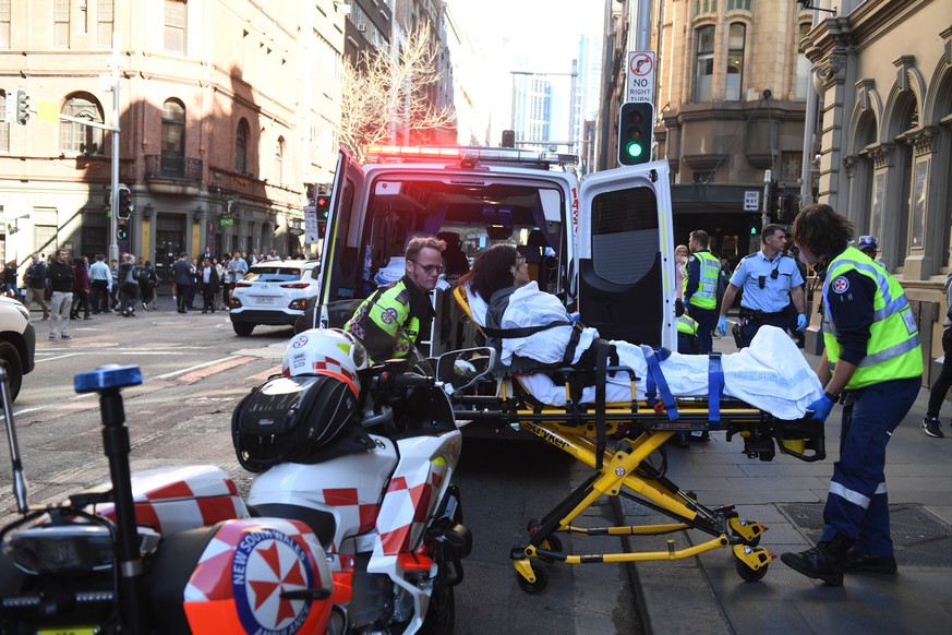 epa07770604 A woman is taken to an ambulance by paramedics in Sydney, Australia, 13 August 2019. According to media reports a police operation is underway in Sydney&#039;s CBD after a person wearing a ...