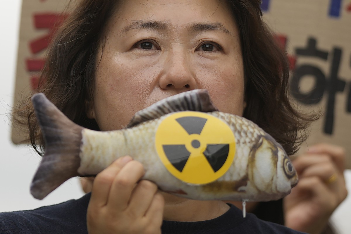 A member of environmental group holds a mock fish during a rally to demand the stop of the Japanese government's decision to release treated radioactive water into the sea from the damaged Fukush ...