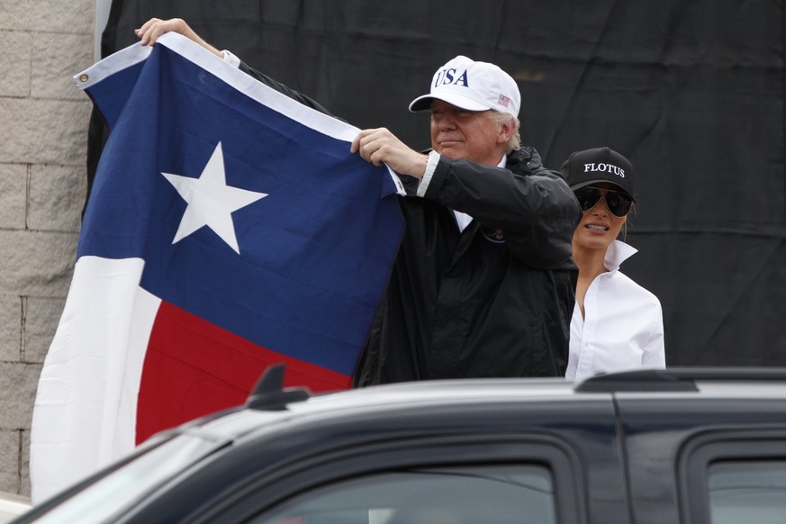 President Donald Trump, accompanied by first lady Melania Trump, holds up a Texas flag after speaking with supporters outside Firehouse 5 in Corpus Christi, Texas, uesday, Aug. 29, 2017, , where he re ...