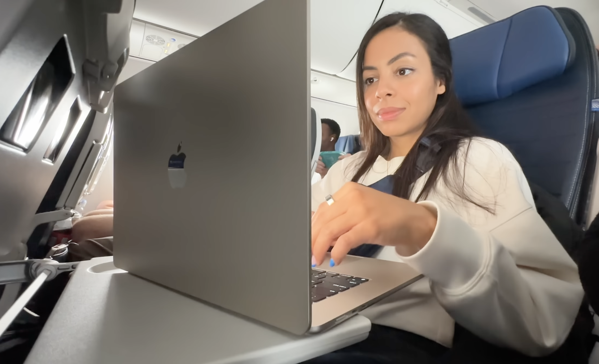 YouTuberin mit Macbook Air 15" (2023) an Bord eines Passagierflugzeugs.