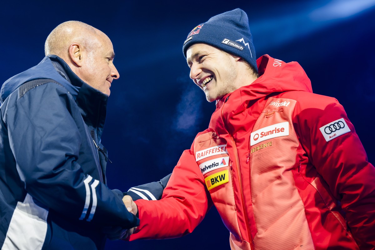 epa10457462 Fourth placed Marco Odermatt (R) of Switzerland talks with Johan Eliasch, President of the International Ski Federation, FIS, during the medal ceremony for the Men's Super-G race at t ...