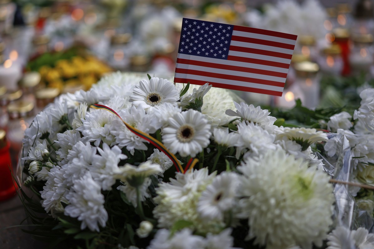 A U.S. national flag and flowers in memory of three soldiers found dead on Monday at a training range in Pabrade, are on the ground near the U.S. Embassy in Vilnius, Lithuania, Tuesday, April 1, 2025. ...