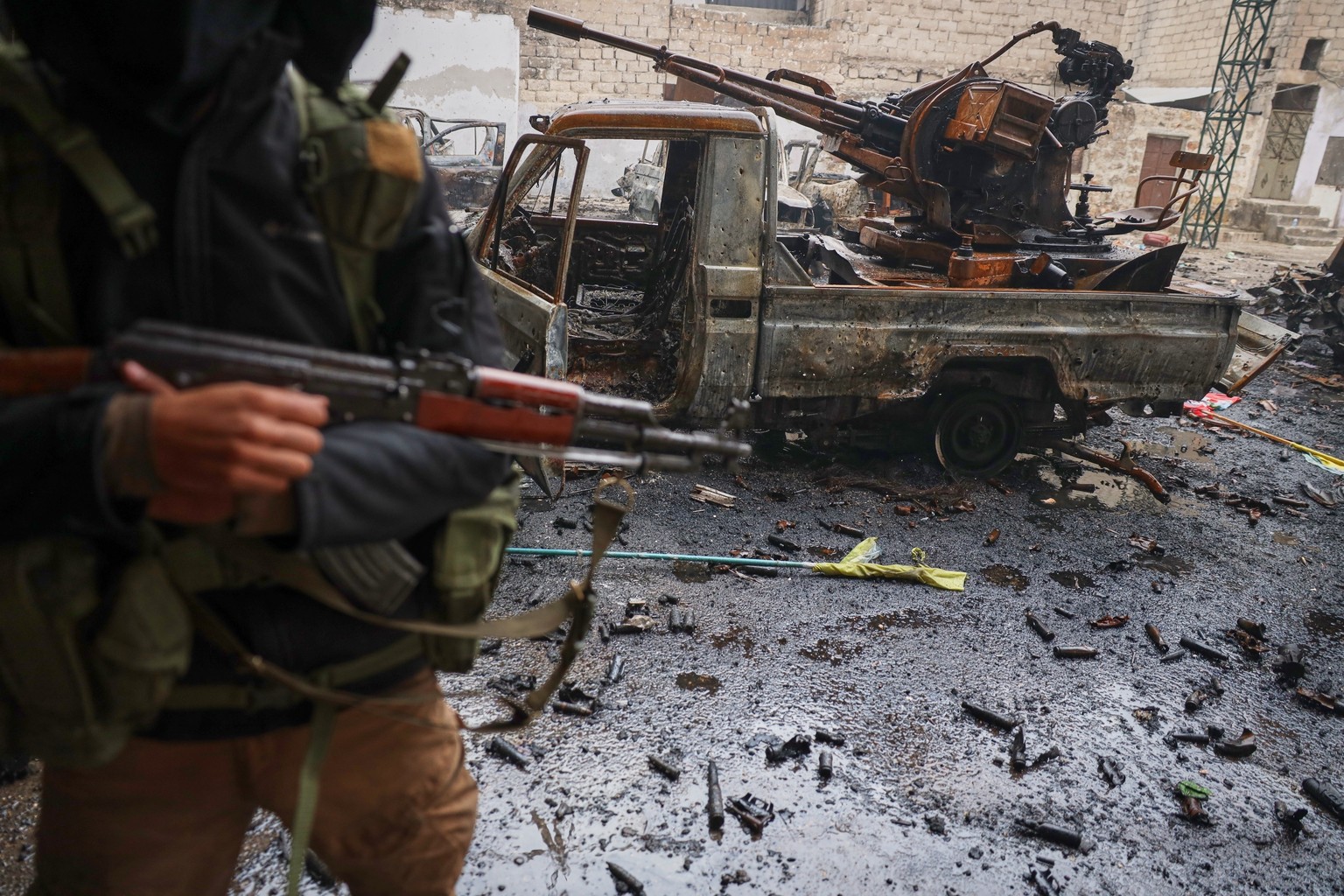 FILE - A member of Syrian security forces stands next to a destroyed vehicle in the predominantly Kurdish Sheikh Maqsoud neighborhood where clashes broke out Tuesday Jan. 6 between government forces a ...