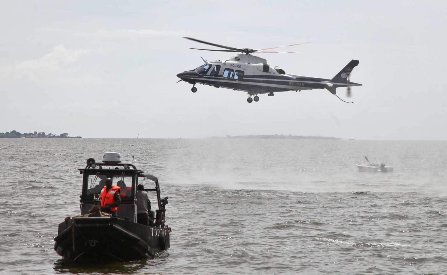 A helicopter searches for victims of a boat which capsized in Lake Victoria near the capital, Kampala, Uganda Sunday, Nov. 25, 2018. Ugandan diving teams are retrieving bodies from Lake Victoria where ...