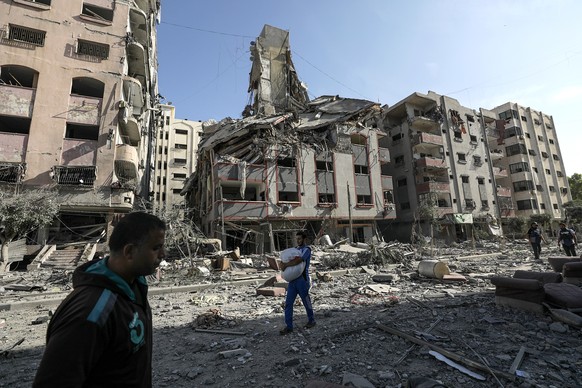 epa10949117 Palestinians walk among the rubble of destroyed residential buildings following Israeli air strikes on Tel al-Hawa neighborhood, in Gaza City, 30 October 2023. The IDF struck over 600 mili ...