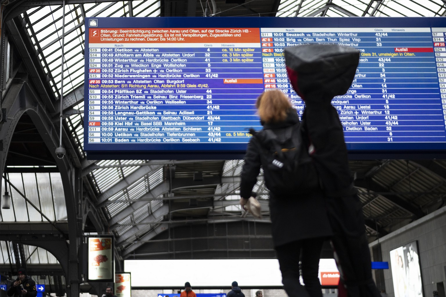 Reisende betrachten die grosse SBB-Anzeigetafel im Hauptbahnhof Zuerich und erkundigen sich nach dem Zugverkehr, da ein Teil des Verkehrs zwischen Olten und Aarau unterbrochen ist, fotografiert am Mit ...