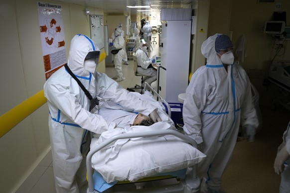 Medics wearing special suits to protect against coronavirus move a patient with coronavirus at an ICU at the Moscow City Clinical Hospital 52, in Moscow, Russia, Tuesday, Oct. 19, 2021. Russia hit ano ...