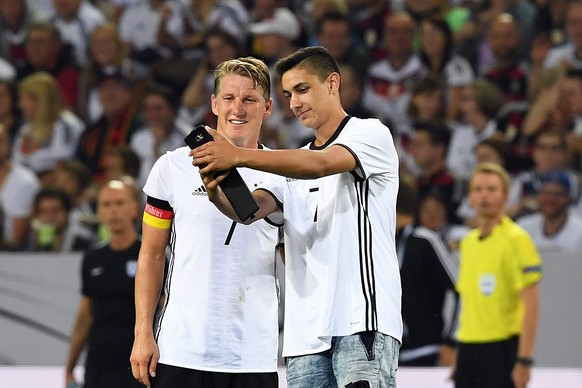 epa05517515 A pitch invader takes a selfie with Bastian Schweinsteiger of Germany (L) during the international friendly soccer match between Germany and Finland at the Borussia-Park stadium in Moenche ...