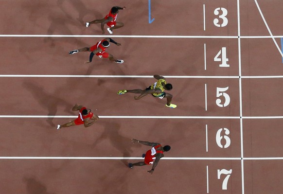 Usain Bolt of Jamaica (3rd from top) runs towards the finish line next to Justin Gatlin of the U.S. (bottom) at the men&#039;s 100 metres final during the 15th IAAF World Championships at the National ...