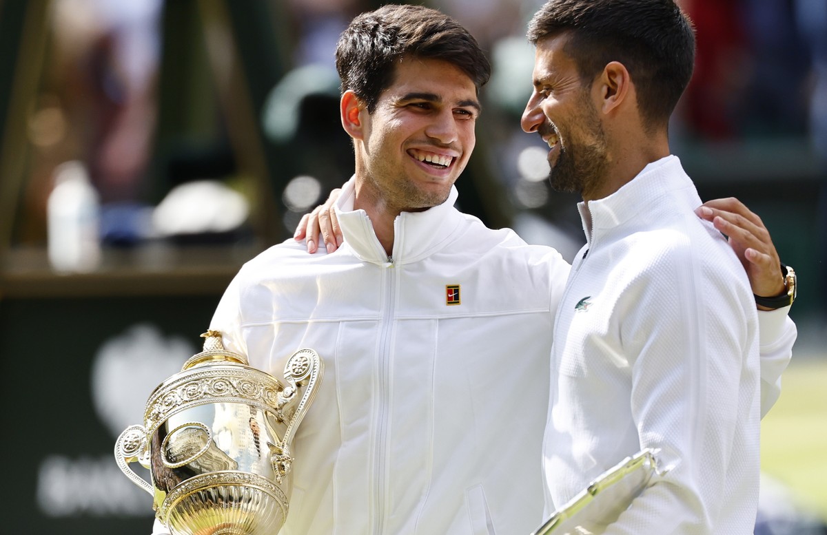 epa11477934 Carlos Alcaraz of Spain (L) celebrates with his trophy after winning the Men's final against Novak Djokovic of Serbia (with his runner-up trophy) at the Wimbledon Championships, Wimbl ...
