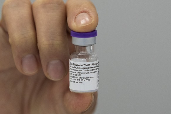 An employee of the Municipal Health Service GGD shows the Pfizer-BioNTech COVID-19 vaccine prior to administering it to a health care worker at a coronavirus vaccination facility in Houten, central Ne ...