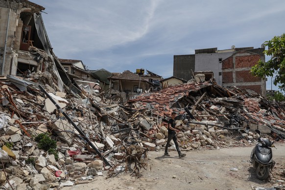 epa10608816 A man walks past wreckage in Hatay, Turkey, 04 May 2023. More than 50,000 people died and thousands more were injured after major earthquakes struck southern Turkey and northern Syria on 0 ...