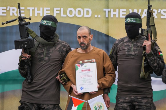 FILE - Israeli captive, Eli Sharabi, who has been held hostage by Hamas in Gaza since October 7, 2023, stands on a stage escorted by Hamas fighters before being handed over to the Red Cross in Deir al ...