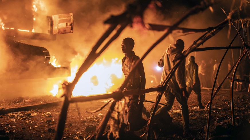 People walk by U.N. vehicles which were set on fire by angry crowds frustrated over the advance of M23 rebels, in Goma, Democratic Republic of Congo, Tuesday, Nov. 1, 2022. The violence came amid fals ...