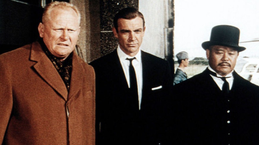 Bösewicht Auric Goldfinger (Gert Fröbe), James Bond (Sean Connery) und Oddjob (Harold Sakata).