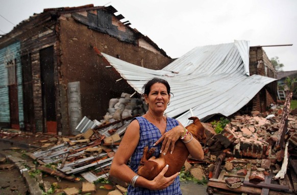 epa06195752 A woman poses with her dog in fron of her destroyed house after the Hurricane Irma, at the central city of Remedios, Cuba, 9 September 2017. The central region of Cuba woke up today in one ...