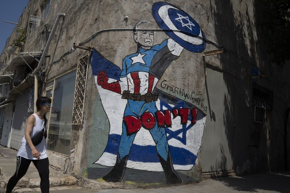 A man walks past a mural depicting the U.S. president Joe Biden as a superhero defending Israel on a street in Tel Aviv, Israel, Sunday, April 14, 2024. Israel on Sunday hailed its successful air defe ...