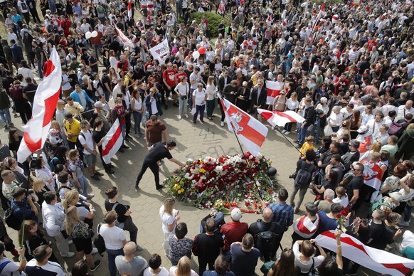 People with old Belarusian National flags lay flowers as they gather at the place where Alexander Taraikovsky died amid the clashes protesting the election results, during his civil funeral in Minsk,  ...