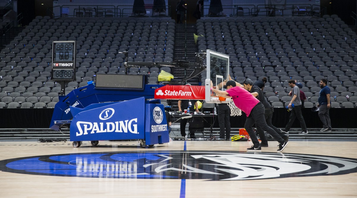 Crews remove a basketball hoop from the court after the Dallas Mavericks defeated the Denver Nuggets in an NBA basketball game on Wednesday, March 11, 2020 at American Airlines Center in Dallas. The N ...