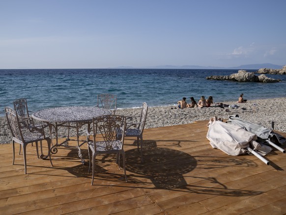 People sit on at a beach in Kokkari , in front of a tavern on the eastern Aegean island of Samos, Greece, Tuesday, June 8, 2021. About a month after Greece officially opened to international visitors, ...
