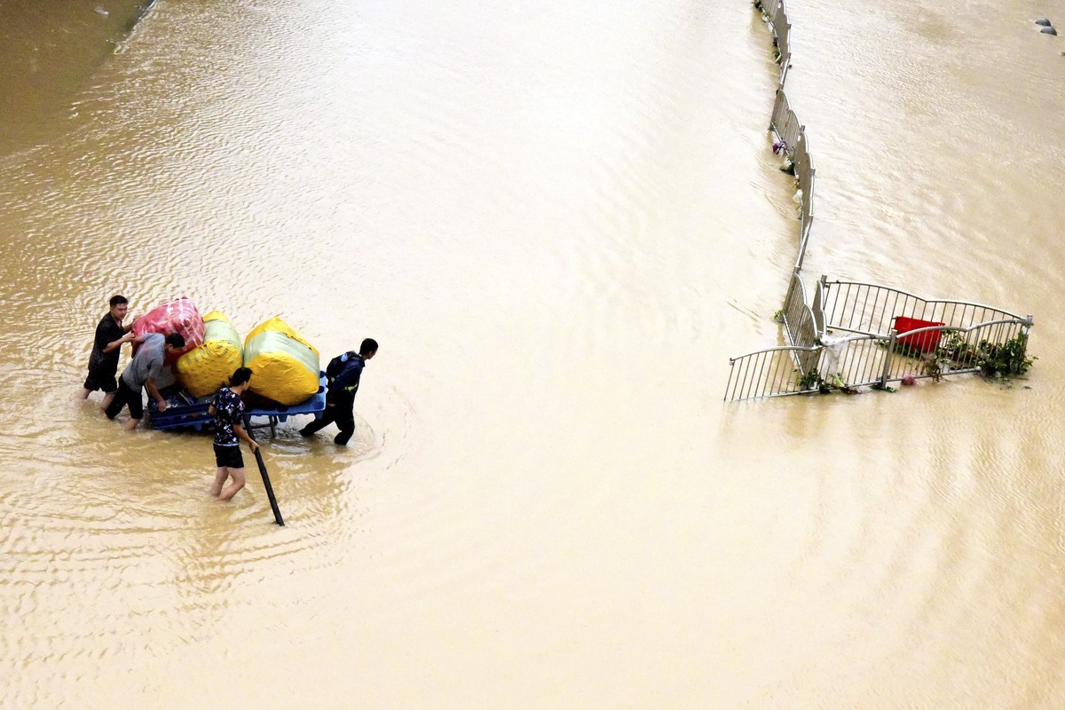 In this photo released by Xinhua News Agency, residents move their belongings across a flooded street in Zhengzhou in central China's Henan province on Wednesday, July 21, 2021. China's mili ...