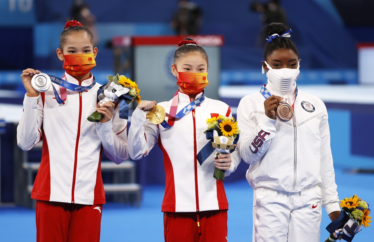 epa09390693 (L-R) - Silver medalist Tang Xijing of China, Gold medalist Guan Chenchen of China and Bronze medalist Simone Biles of USA pose on the podium after the Women's Balance Beam final duri ...