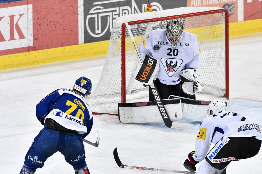 Der Davoser Enzo Corvi, links, prueft Fribourgs Torhueter Reto Berra und Marc Abplanalphes, rechts versucht zu verteidigen, im Eishockey-Qualifikationsspiel der National League zwischen dem HC Davos u ...