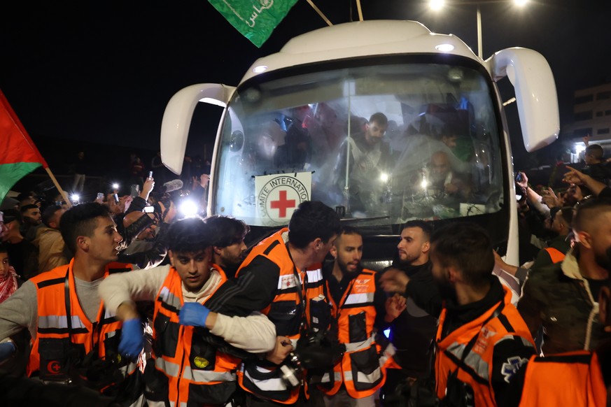 epa10993190 Emergency services try to clear the way as a vehicle of the International Committee of the Red Cross (ICRC) with freed Paletsinian prisoners onboard, leaves the Isareli Ofer military priso ...