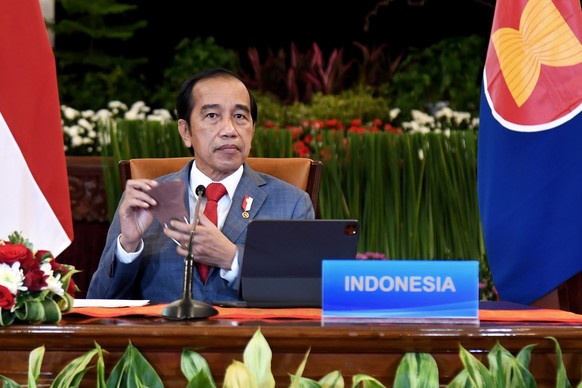 In this photo released by Indonesian Presidential Palace, Indonesian President Joko Widodo removes his mask during the virtual ASEAN-China leaders&#039; summit at the State Palace in Jakarta, Indonesi ...