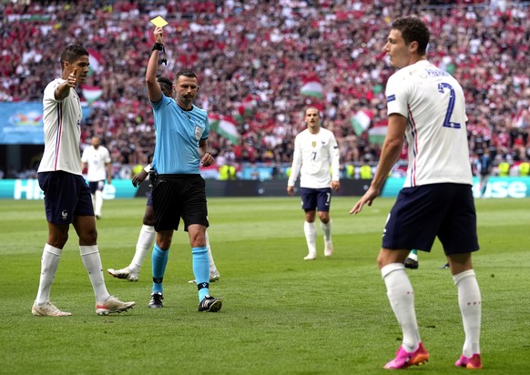 epa09285350 Benjamin Pavard (R) of France is booked by English referee Michael Oliver (2-L) during the UEFA EURO 2020 group F preliminary round soccer match between Hungary and France in Budapest, Hun ...