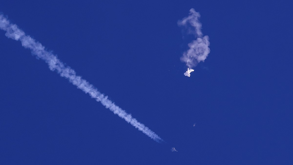 In this photo provided by Chad Fish, the remnants of a large balloon drift above the Atlantic Ocean, just off the coast of South Carolina, with a fighter jet and its contrail seen below it, Feb. 4, 20 ...