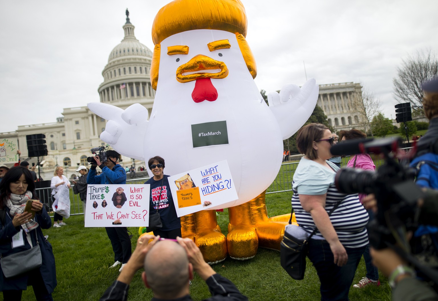 epa05910013 Protestors who gathered outside the US Capitol to call on President Donald J. Trump to release his tax returns have their photo made next to a depiction of the President as an inflatable c ...