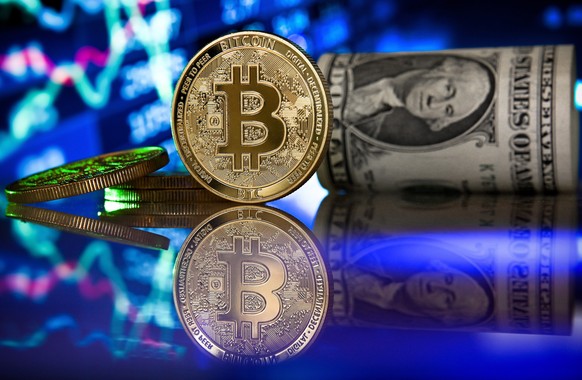 epa09017765 (FILE) - A bitcoin in front of a monitor showing a stock barometer in Duesseldorf, Germany, 20 January 2021 (reissued 17 February 2021). Cryptocurrency Bitcoin's value value crossed the 50 ...