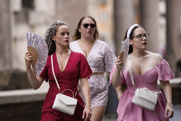 Tourists use foldable fans to cool off as they visit Rome, Saturday, July 22, 2023. An intense heat wave has reached Italy, bringing temperatures close to 40 degrees Celsius in many cities across the  ...