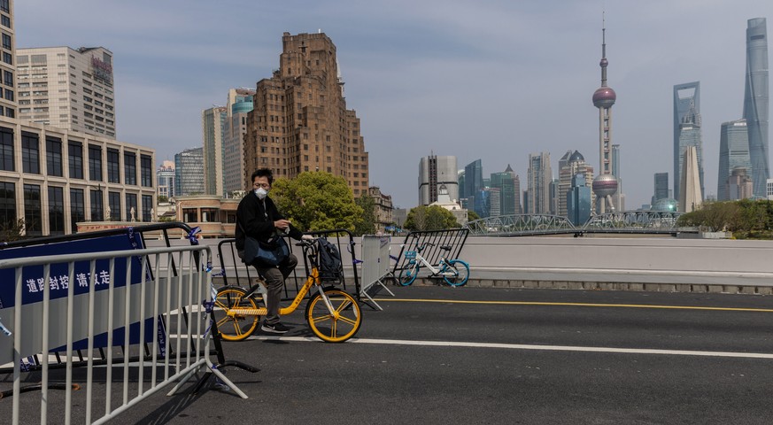 epa09922498 A man rides a bicycle trough barricades on the bridge, amid Covid-19 lockdown of the city in Shanghai, China, 02 May 2022. Shanghai city reported 32 COVID-19 deaths, 727 locally transmitte ...