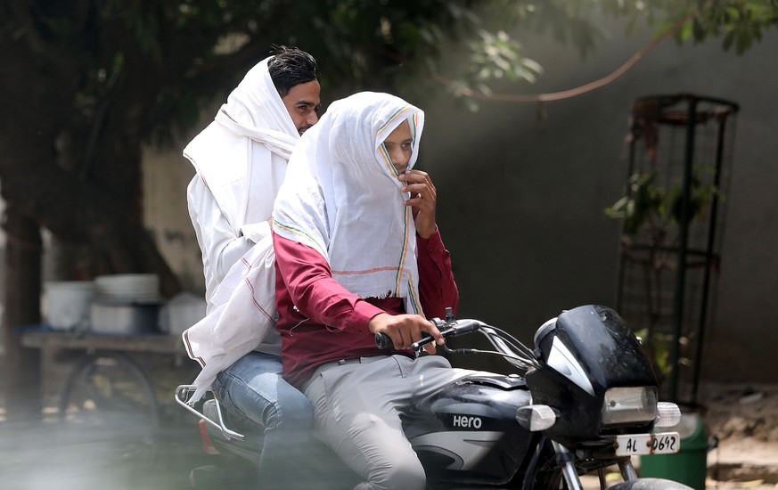 epaselect epa09920055 Men ride a motorcycle during a hot afternoon on the outskirts of New Delhi, India, 01 May 2022. According to the India Meteorological Department (IMD), Delhi and National Capital ...