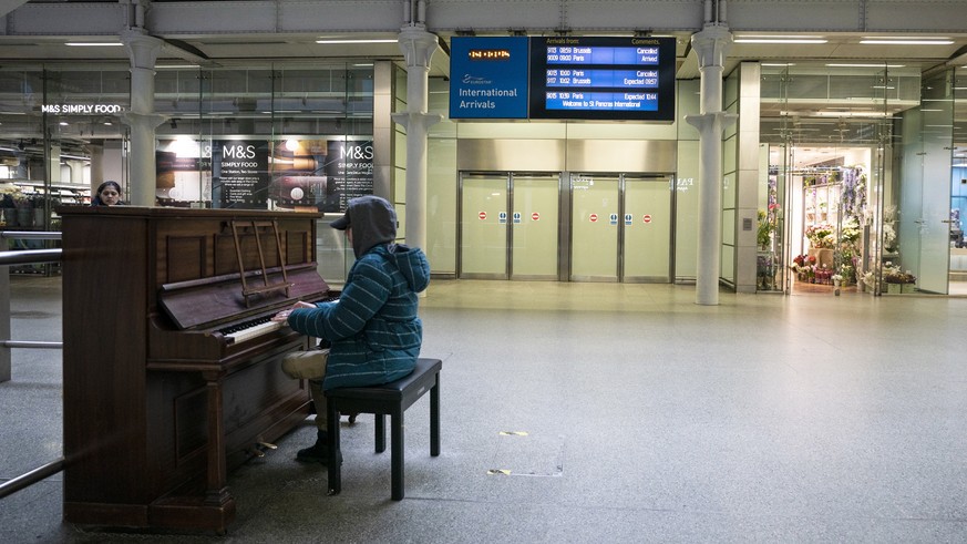 epa08303102 A person plays a piano at King's Cross St Pancras Station in central London, Britain, 18 March 2020. Transport links between the United Kingdom and mainland Europe, including the Euro ...