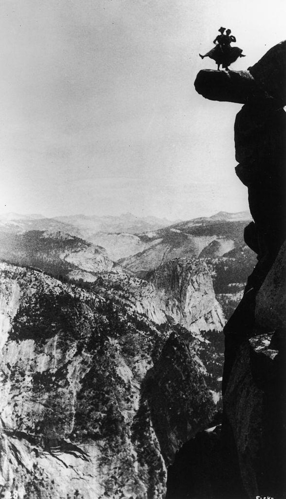 Distant silhouette view of Kitty Tatch and friend photographed by George Fiske as they dance on the overhanging rock at Glacier Point, Yosemite, California, 1890s. (Photo by Fotosearch/Getty Images).