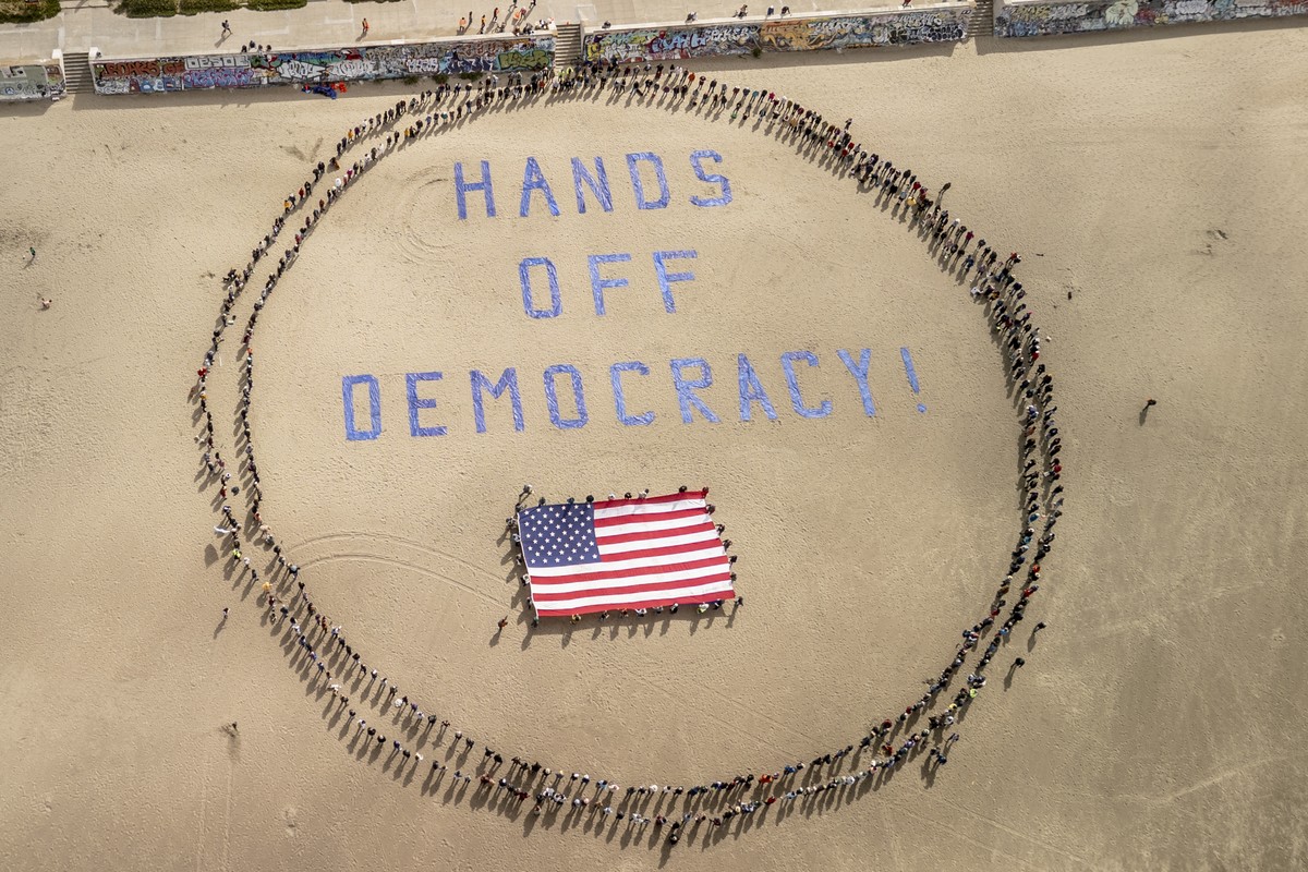 Protesters form a human banner on Ocean Beach during a protest against President Donald Trump, part of the "Hands Off" rallies held nationwide, in San Francisco, Saturday, April 5, 2025. (St ...