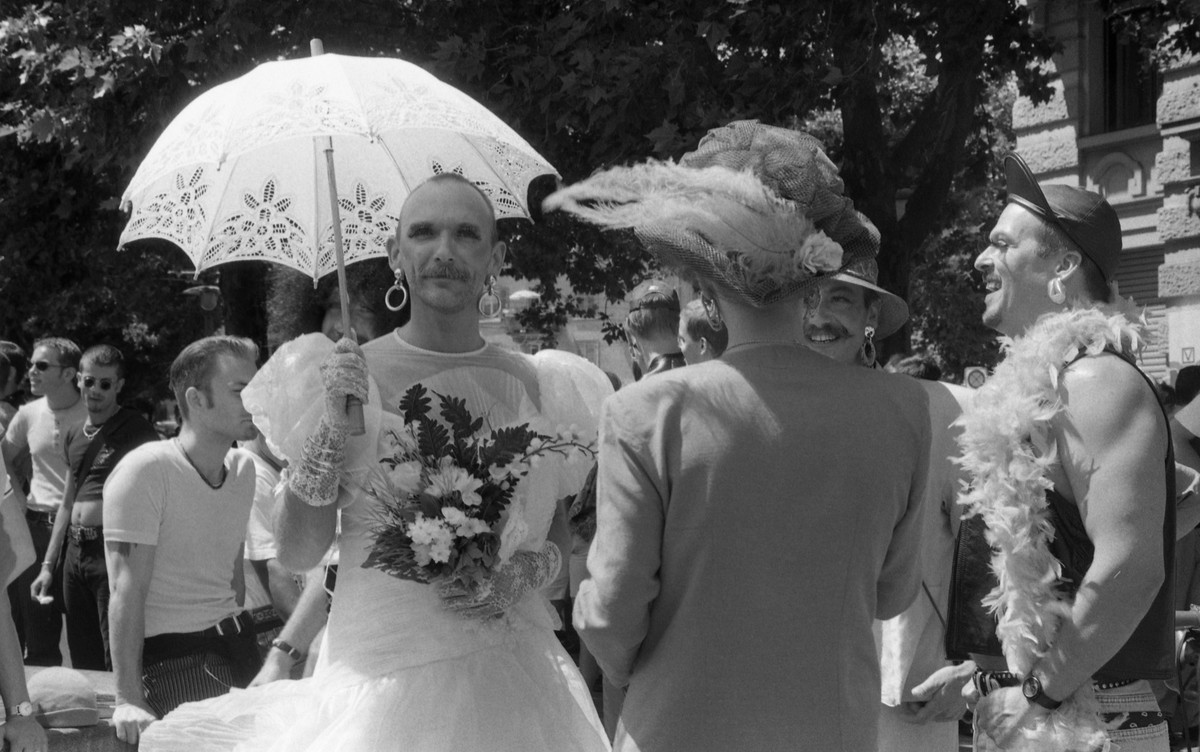 "Christopher Street Day, Zürich, 20.07.1996" - Mann in Brautkleid mit Brautstrauss, Schirm und Schmuck blickt in die Kamera