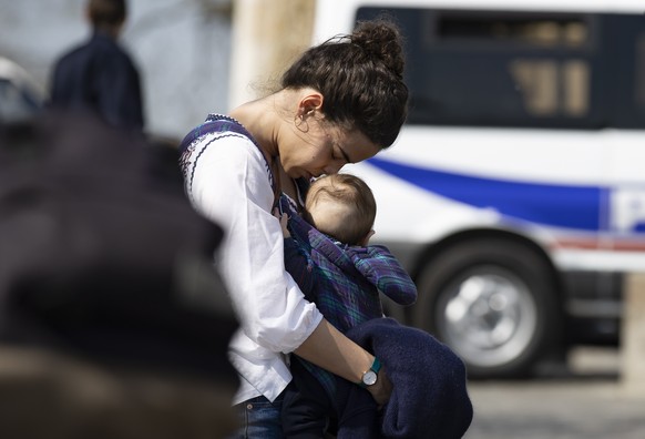 epa08352822 A woman holding her baby prays during a service led by Archbishop Monseigneur Aupetit, performing a Good Thursday blessing in front of Sacre-Coeur (sacred heart) basilica atop Montmartre o ...
