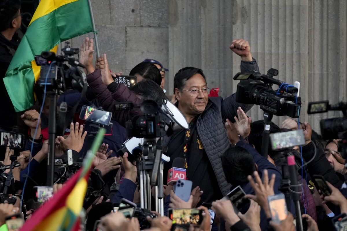 Bolivian President Luis Arce raises a clenched fist surrounded by supporters and media, outside the government palace in La Paz, Bolivia, Wednesday, June 26, 2024. Armored vehicles rammed the doors of ...