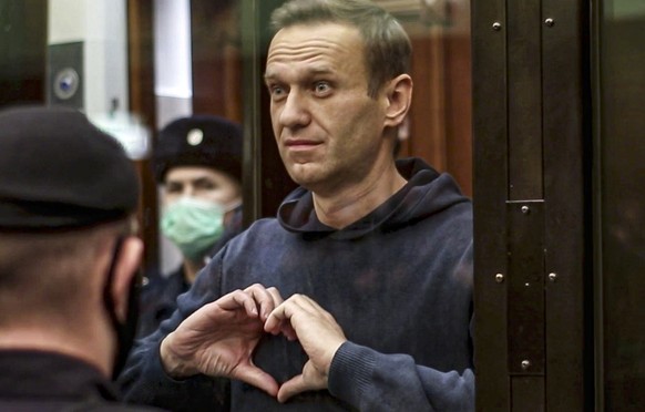 FILE - In this handout photo taken from video provided by the Moscow City Court on Feb. 2, 2021, Russian opposition leader Alexei Navalny shows a heart symbol while standing in a cage for defendants i ...