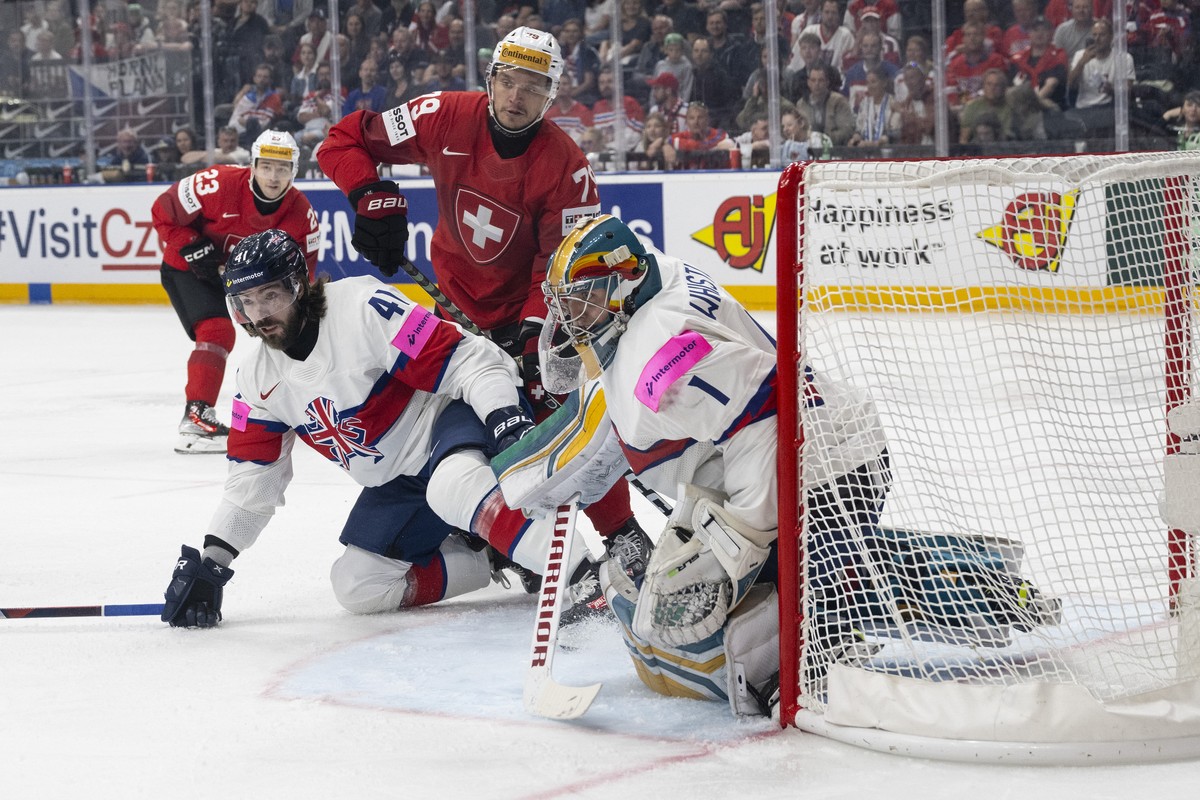 Switzerland's Calvin Thuerkauf, center, in action against Great Britain's Josh Batch, left, and Great Britain's goalkeeper Jackson Whistle during the Ice Hockey World Championship group ...