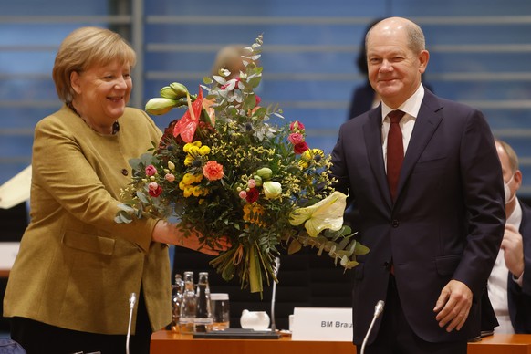 epa09600129 Acting Chancellor Angela Merkel (L) receives a bouquet of flowers from acting Finance Minister and Vice Chancellor Olaf Scholz as she arrives for the weekly government cabinet meeting in B ...