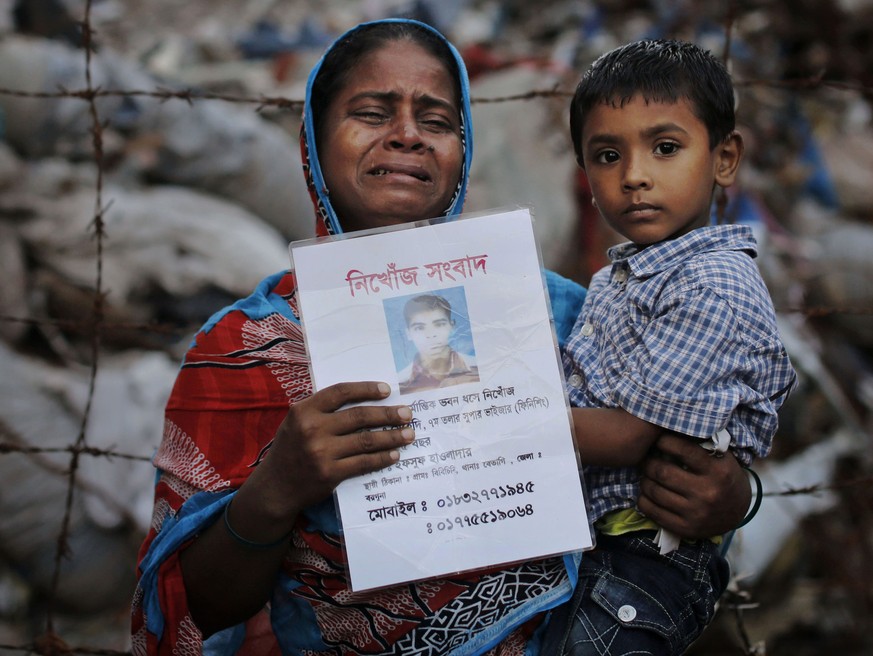 FILE - In this Friday, June 14, 2013 file photo, Bangladeshi Maksuda holds a picture of her son Mehedi who was a garment worker and is missing following the collapse of the Rana Plaza building as she  ...