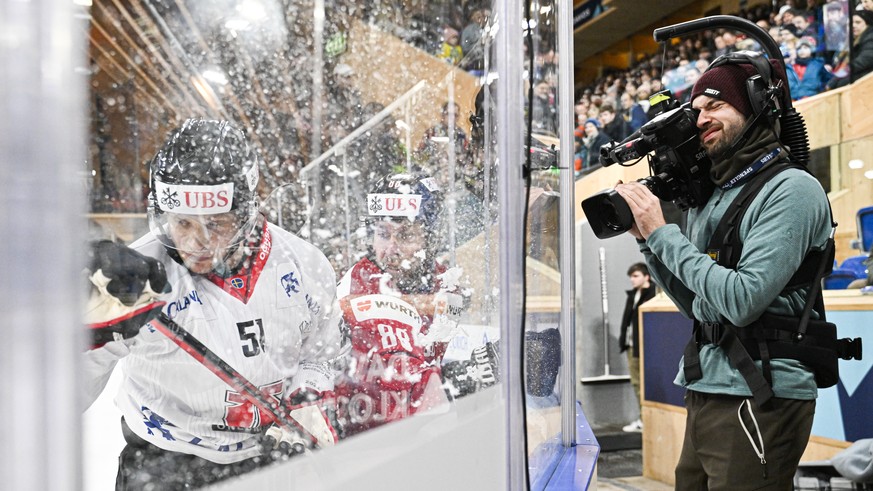 Oerebro&#039;s Kristian Nakyva, left, Canada`s Chris Didomenico and TV Camera during the game between Sweden&#039;s Oerebro HK and Team Canada, at the 94th Spengler Cup ice hockey tournament in Davos, ...