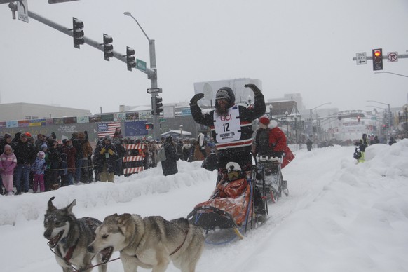 Musher Keaton Loebrich of Fairbanks, Alaska, encourages applause from the crowd as he drives his dog team down Fourth Avenue in downtown Anchorage, Alaska, on Saturday, March 7, 2026, during the cerem ...